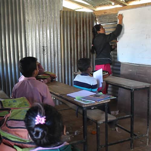 A teacher conducting a lesson to students in a temporary classroom in Nepal