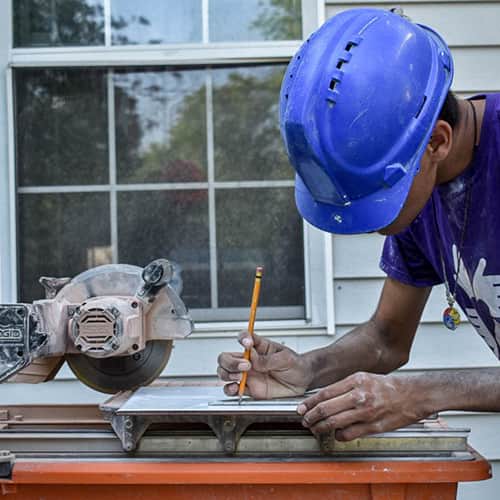 Volunteer-Writing-Measurements-Houston-Texas.jpg An international volunteer drawing out measurements with a pencil for circular sawing, in Houston Texas