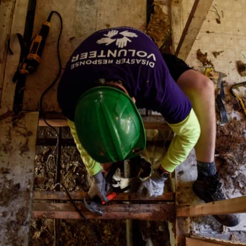 Voluntario internacional martillando la infraestructura interna de una casa en reconstrucción