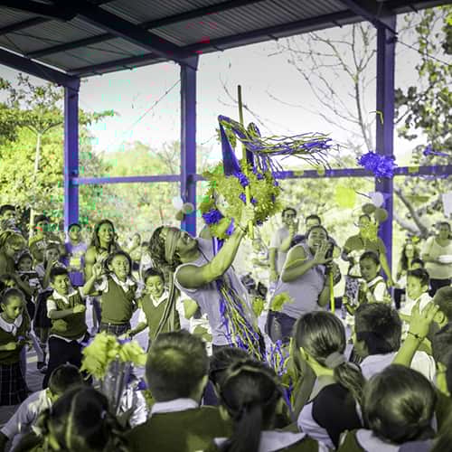 Volunteer-Children-Celebration-Piñata-Mexico.jpg A volunteer smashing a piñata amongst a celebration with young school children in Mexico