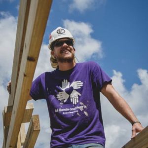 International volunteer smiling whilst standing amongst the framework of a home being built