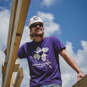 Voluntario internacional sonriendo mientras está de pie en el marco de una casa en construcción