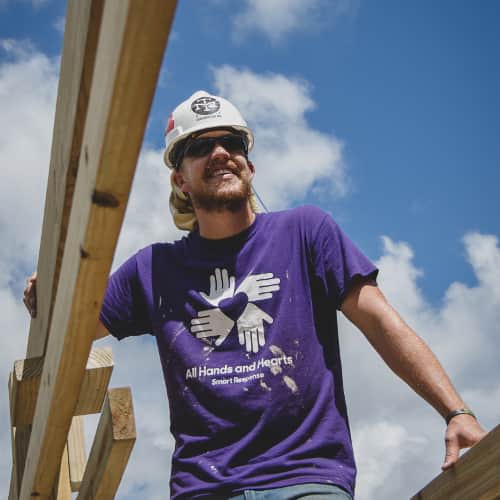 Volunteer-Smiling-Disaster-Rebuild.jpg International volunteer smiling whilst standing amongst the framework of a home being built