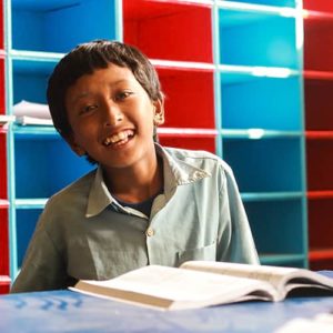 Un joven y sonriente estudiante de Nepal sonriendo en un aula de una escuela recién construida