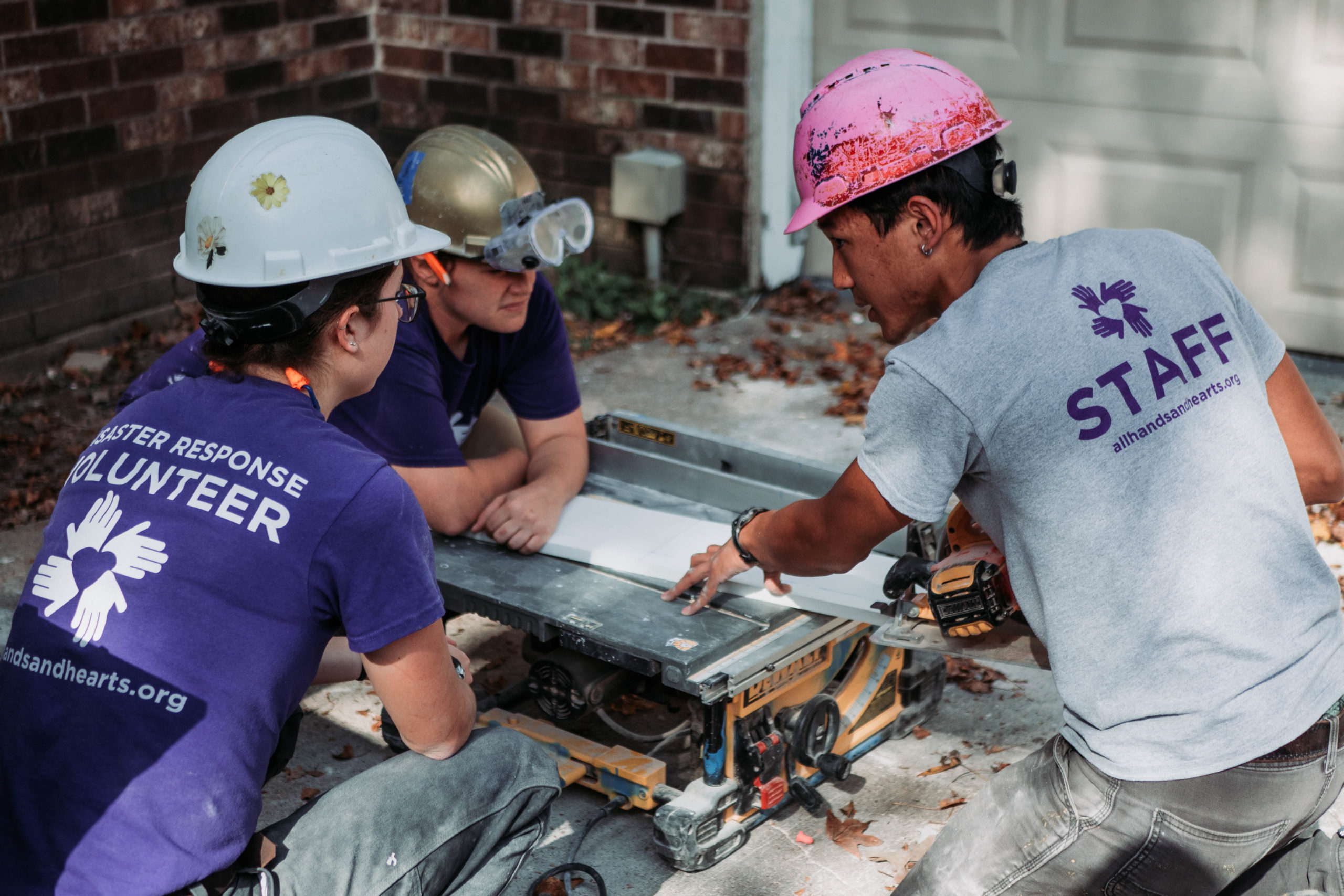 staff explaining to two volunteers on a tablesaw