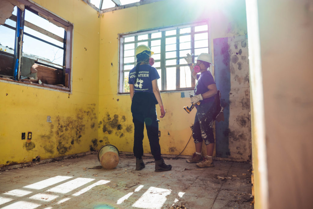 two volunteers in a moldy room after a hurricane