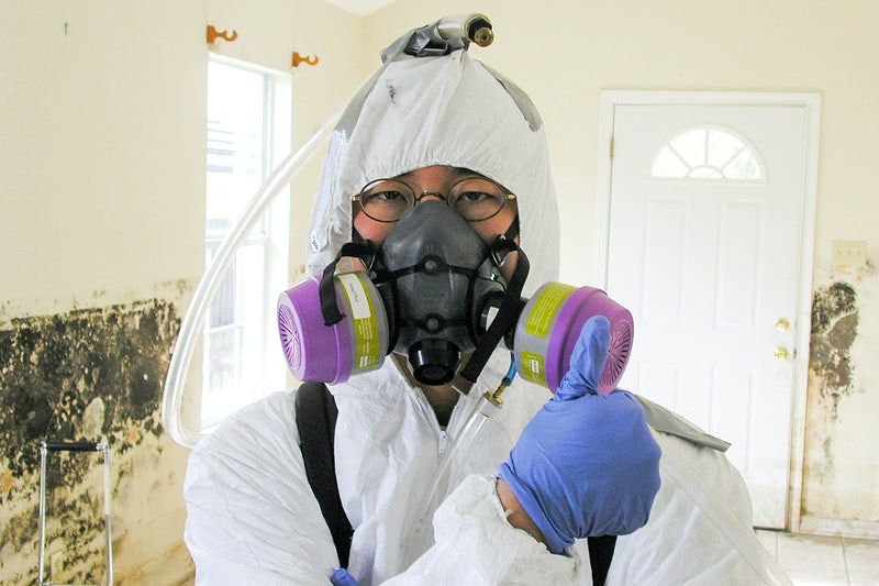 person in tyvek and a respirator giving a thumbs up