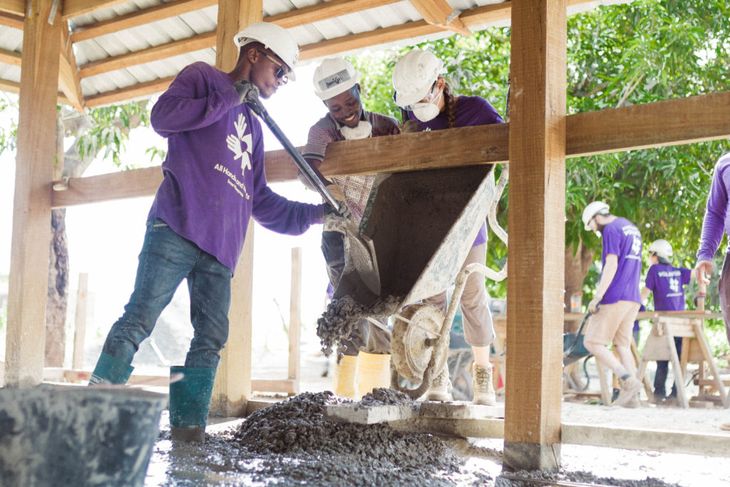 volunteers pouring concrete from a wheelbarrow