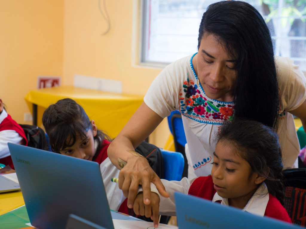 teacher showing a student something on a laptop