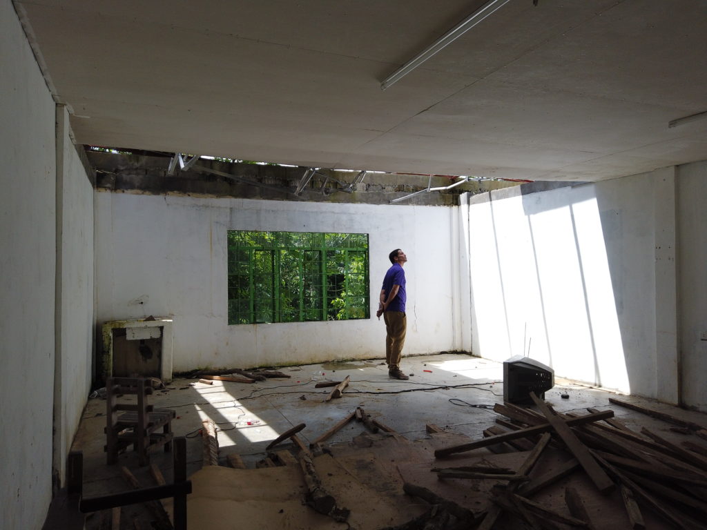 staff standing under a whole in the roof of a damaged school