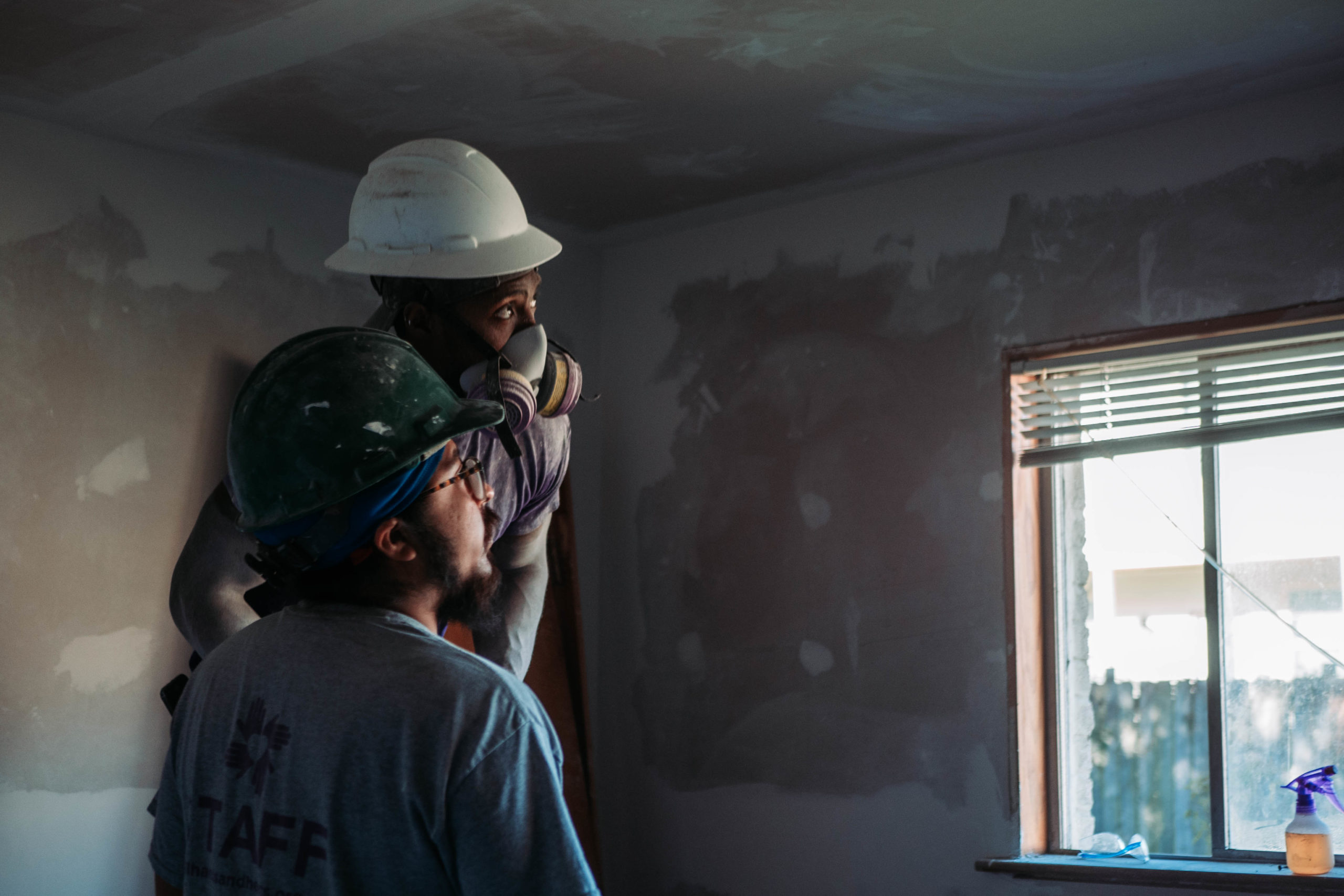 two people looking at a window in hardhats