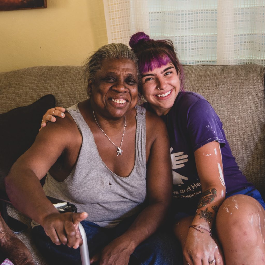 volunteer and a beneficiary hugging on a couch