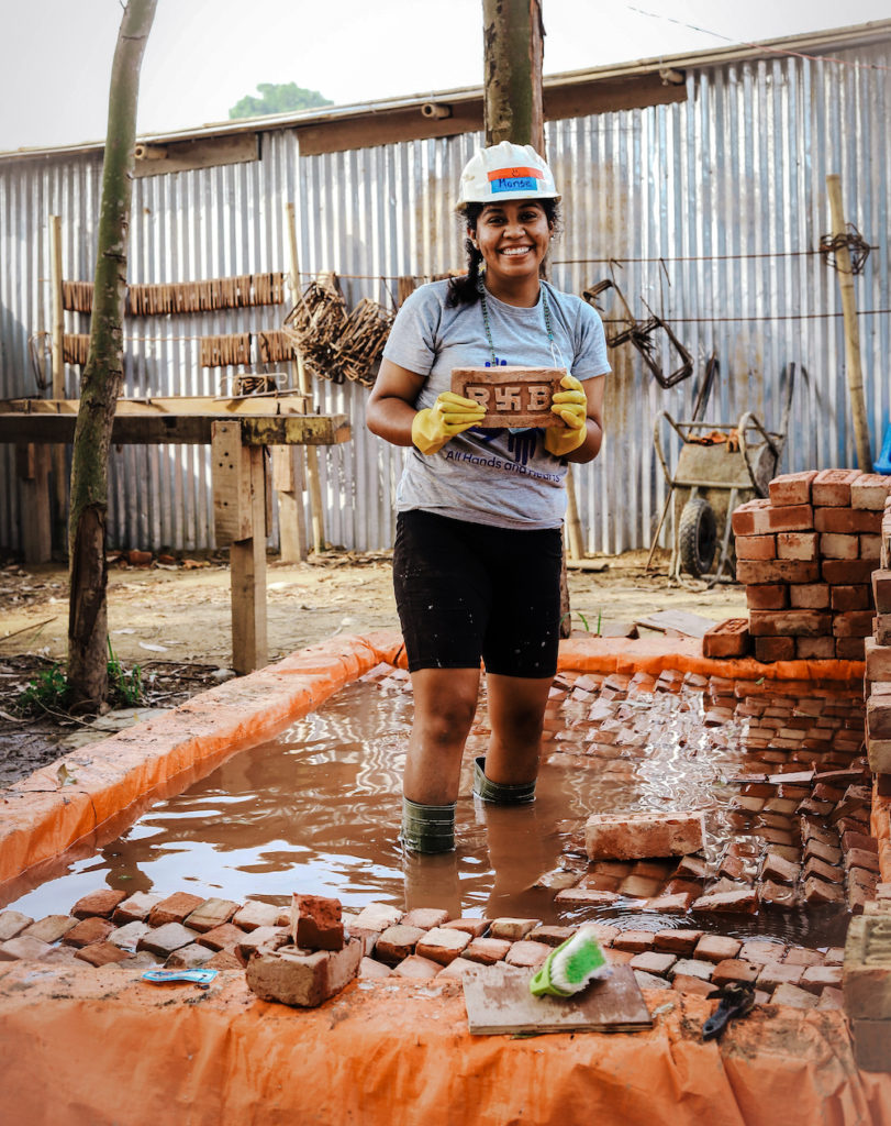 Una voluntaria nepalí sonríe al apilar ladrillos. 