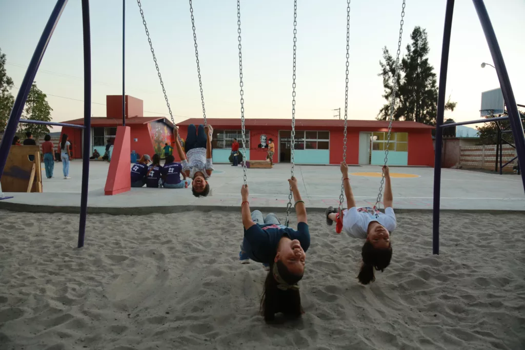 Children playing on swing set at newly constructed school in Mexico