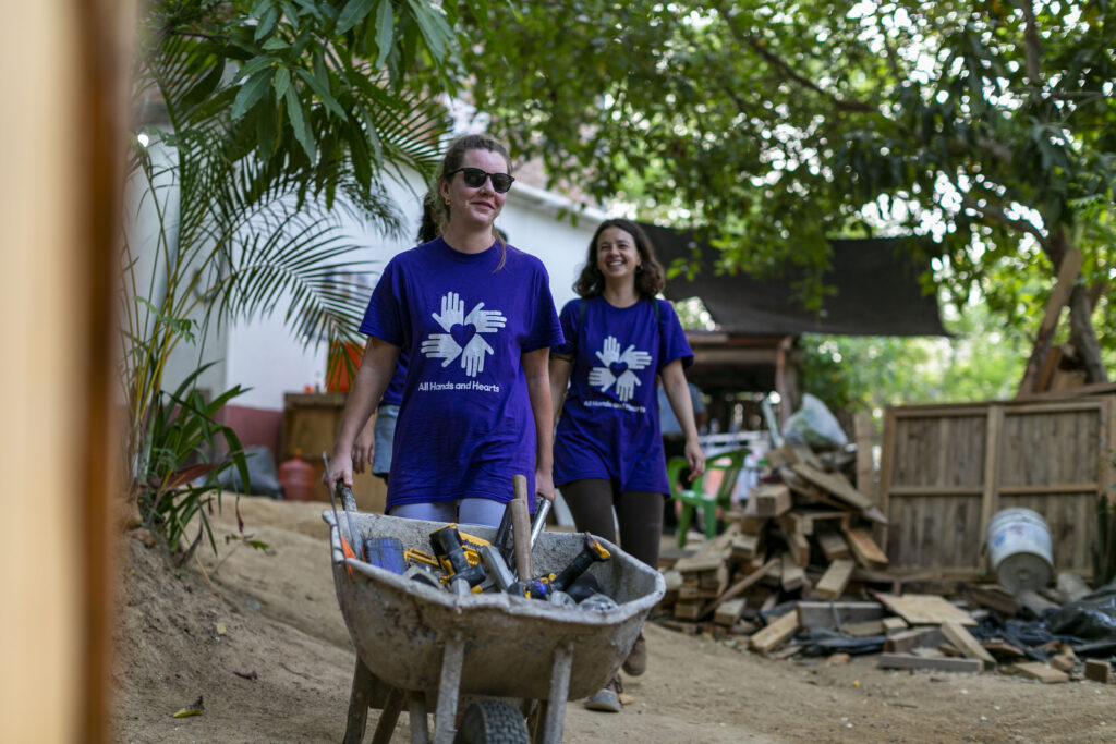 Two volunteers pushing wheelbarrows of equipment for a school build in Mexico