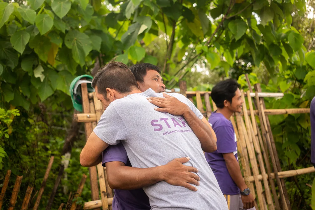 Un miembro del personal y un voluntario se abrazan