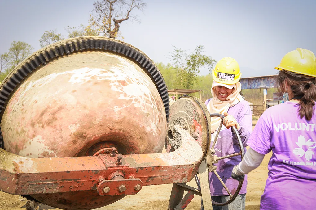 Two volunteers operating a cement mixer